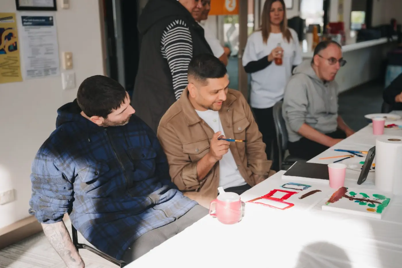 Participants and support workers chatting around a table