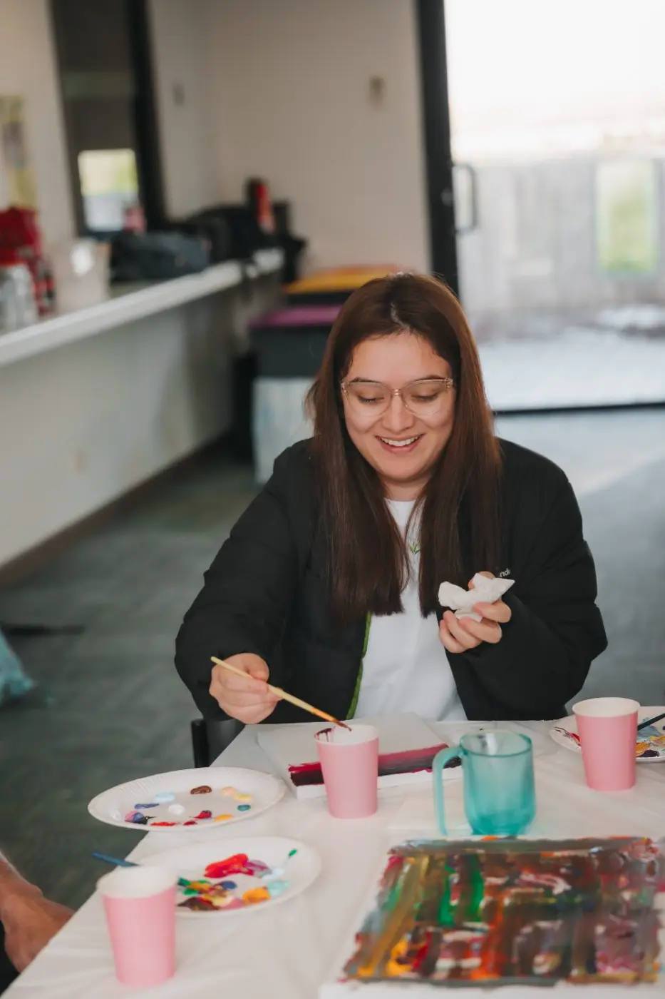 Smiling participant painting at a table during a group activity