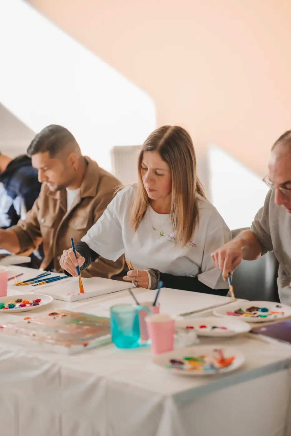 Participants and support workers painting and laughing together