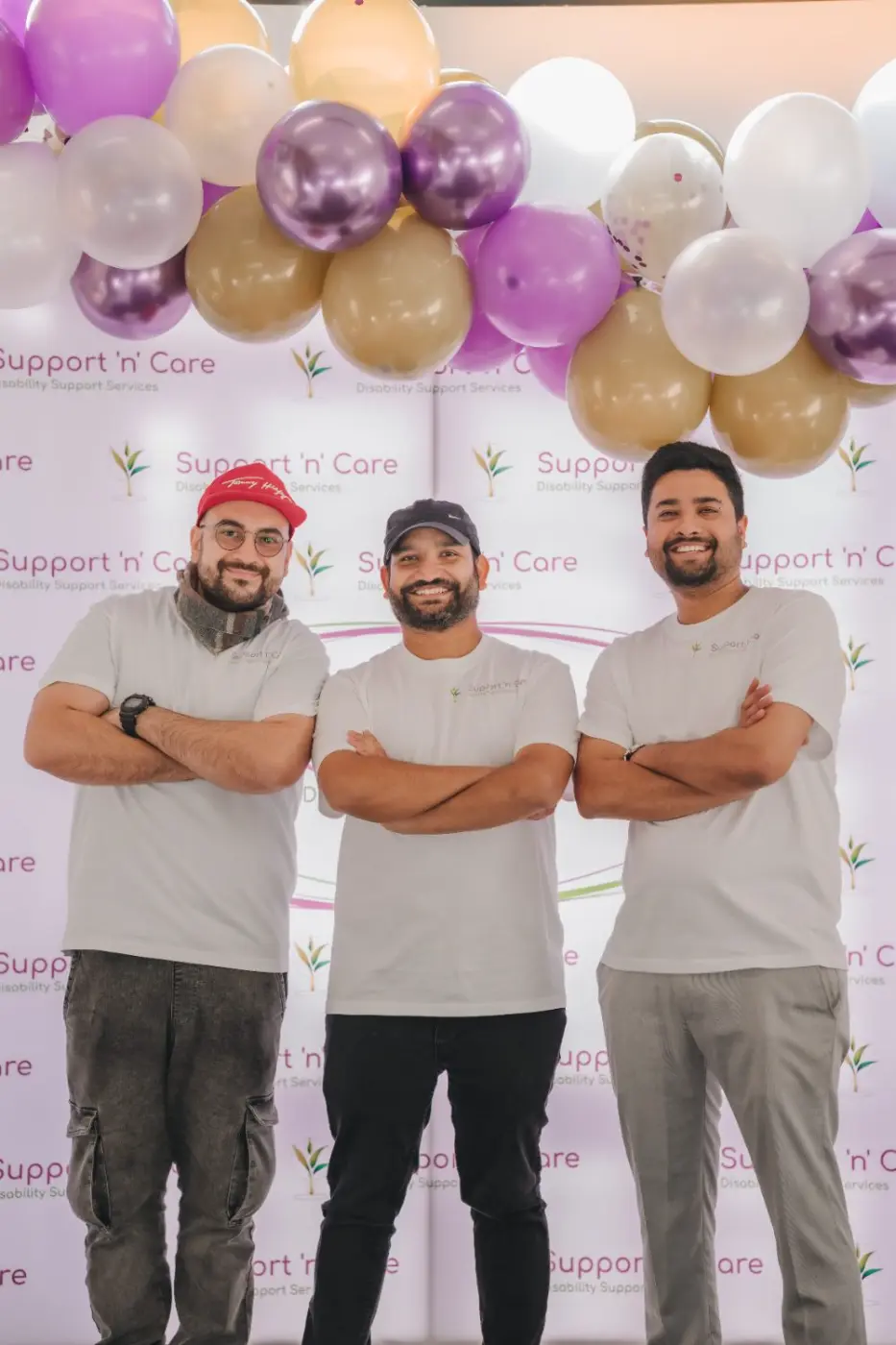 Three team members standing together in front of a balloon backdrop