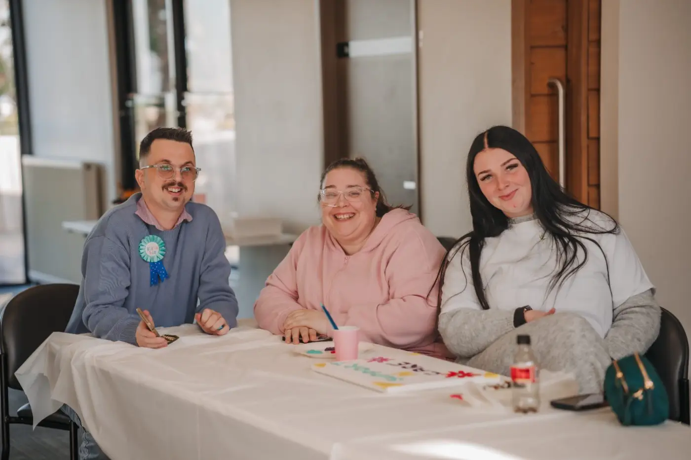 Three people smiling together at a table during a group activity