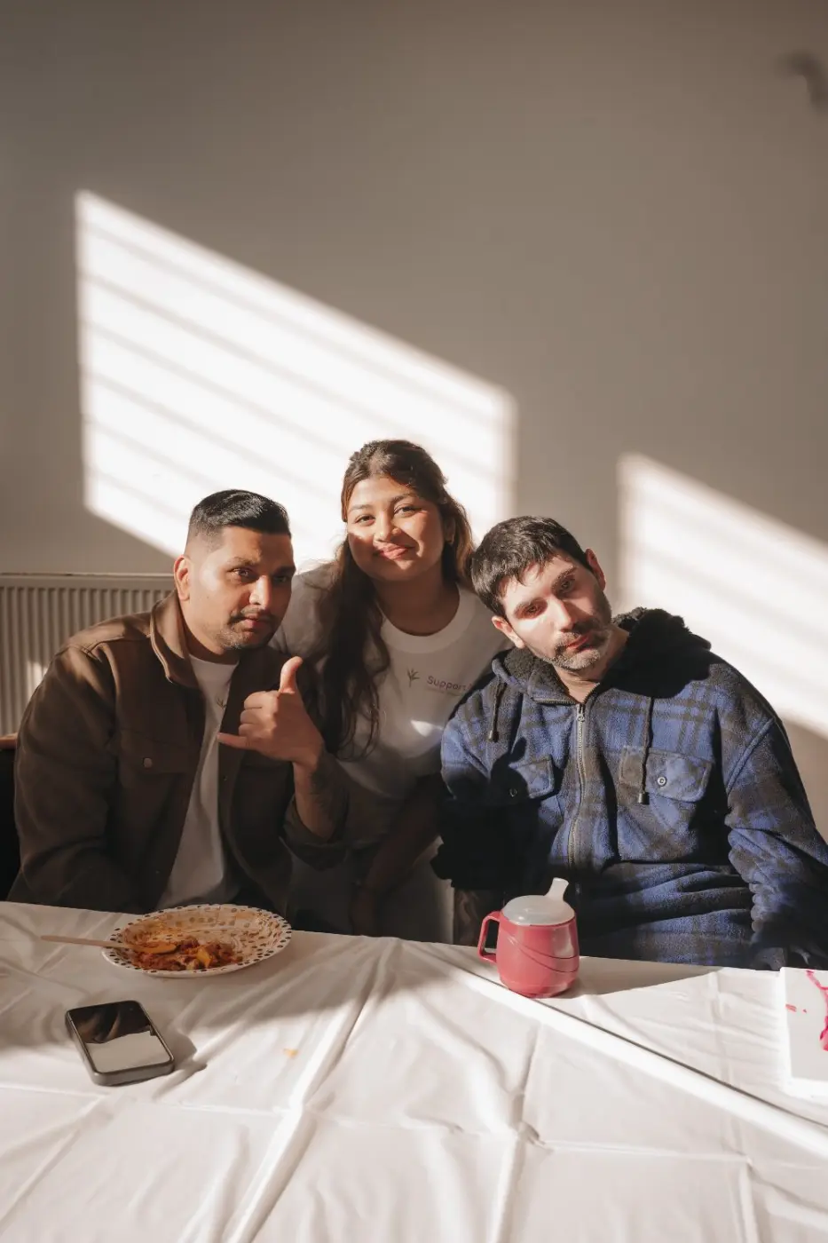 Participants and a support worker smiling together at a table