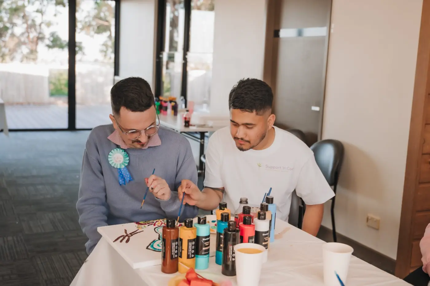 Two participants painting side by side at a table