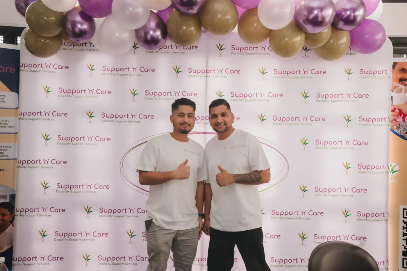 Two team members posing in front of a balloon backdrop