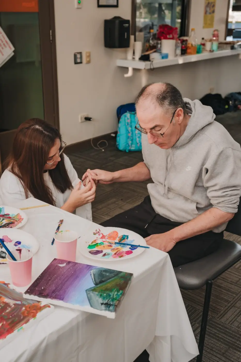 Participant painting a colourful canvas at a table