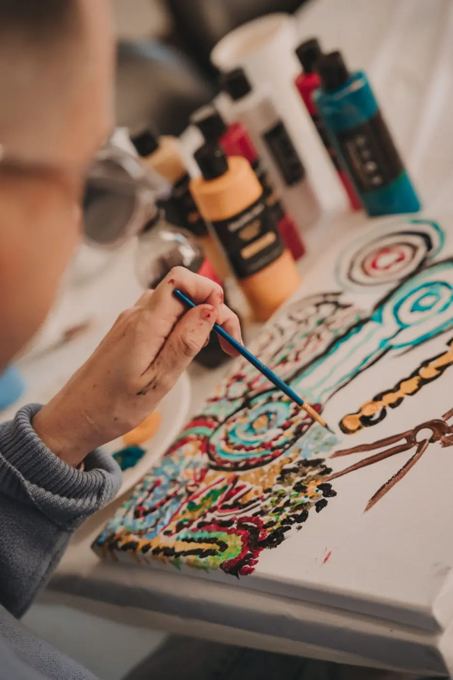 Close-up of a participant painting a detailed, colourful design