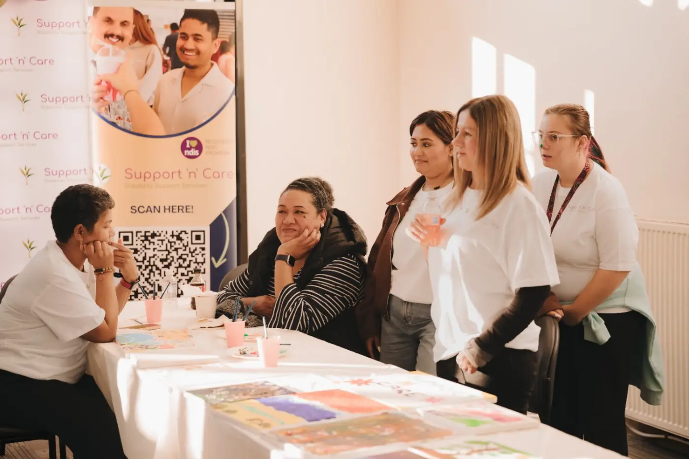 Participants and support workers seated at a long table during a group activity