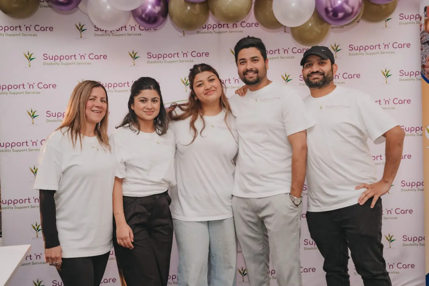 My Support and Care team members standing together in front of a balloon backdrop