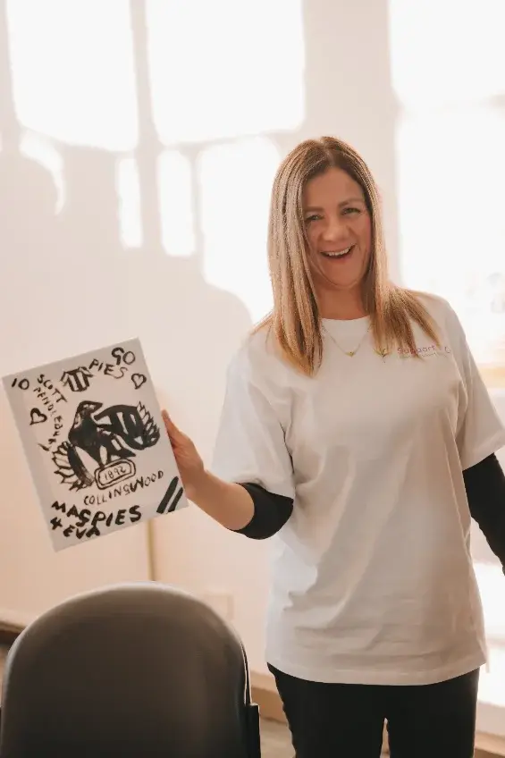 Support worker holding up a participant’s artwork