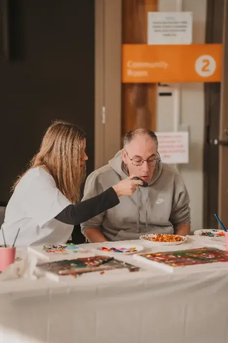 Support worker and participant painting together