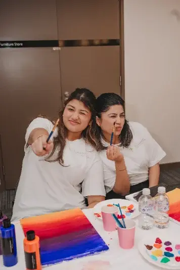 Two team members laughing together at an art table