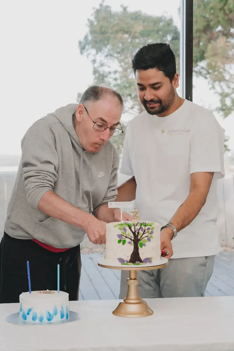 Participant and team member cutting a celebration cake together